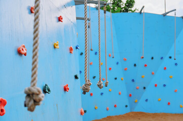 outdoor climbing wall features colorful holds and hanging ropes, offering a challenging and engaging activity space for adventure enthusiasts and fitness seekers in recreational settings
