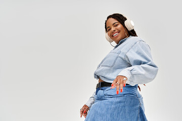 Stylish woman with braids showcases denim fashion while posing in a studio