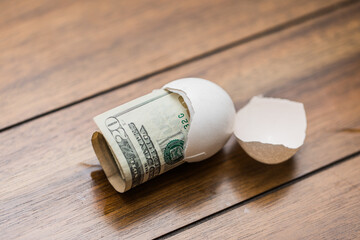 a rolled up twenty dollar bill in a broken eggshell to represent an increase of prices on food 