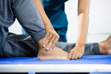 Physiotherapist assists patient with leg and ankle movement therapy during recovery session. Medical care, mobility training, and muscle rehabilitation