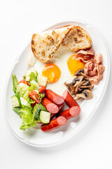 A classic breakfast plate with sunny-side-up eggs, crispy bacon, grilled sausages, sautéed...