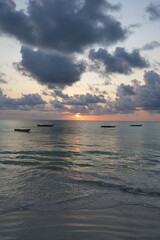 View to sunrise over Indian Ocean and fishing boats in African Zanzibar island in Tanzania - vertical