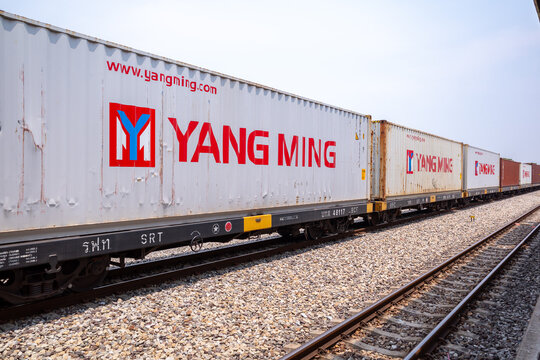 Hua Takhe, Thailand - March 23 2025 : View of Yang Ming Marine Transport Corporation box car which is part of a cargo train passing Hua Takhe Station, Thailand.