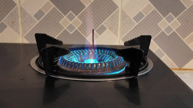 Turntable gas stove burner with blue flame isolated on black metal in a white kitchen