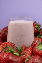 Strawberry milkshake in a glass among fresh ripe strawberries.