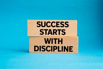 Success starts with discipline message written on wooden blocks on blue background. Conceptual...