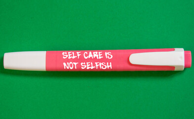 Self care is not selfish message written on pink marker pen on green background. Conceptual self...