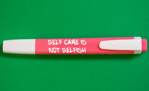 Self care is not selfish message written on pink marker pen on green background. Conceptual self care is not selfish symbol. Copy space.