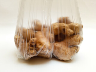 Fresh ginger roots or ginger rhizome in a PVC plastic bag isolated on white background, close up