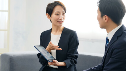 ロビーでタブレットを見ながら商談する男女ビジネスパーソンのグループ