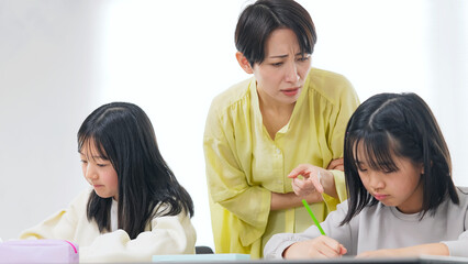 勉強する二人の女の子と厳しく指導する女性