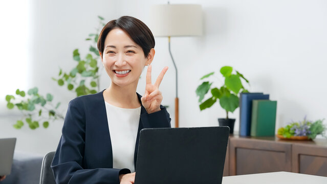 オフィスでピースサインを見せる女性ビジネスパーソン