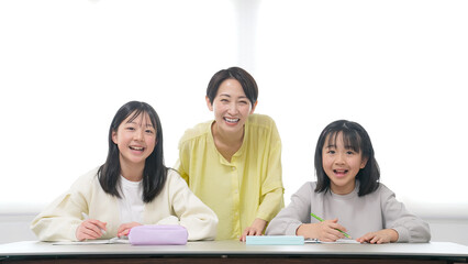 笑顔で勉強する二人の女の子と女性教員