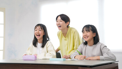 笑顔で勉強する二人の女の子と女性教員
