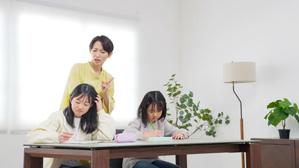 勉強する二人の女の子と厳しく指導する女性