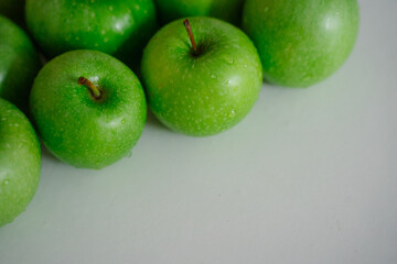 Bright green apples on a white surface, emphasizing their freshness and beauty. The healthy fruit looks inviting and creates a refreshing visual appeal