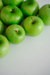Bright green apples on a white surface, emphasizing their freshness and beauty. The healthy fruit looks inviting and creates a refreshing visual appeal.