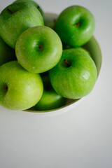 a close-up of fresh green apples in bowl invites viewers to appreciate their glossy texture and vibrant color. These apples look ready to be enjoyed
