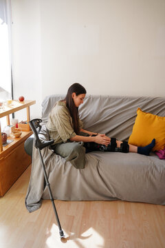 Teen girl adjusting knee brace on broken leg at home