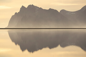 Misty mountain reflection on calm water in Iceland