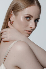 Model showcases elegant beauty in a studio setting with soft lighting and neutral background, highlighting subtle makeup and hair styling