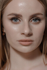 Close-up portrait of a young woman with blue eyes and long hair in neutral lighting showcasing a natural beauty look