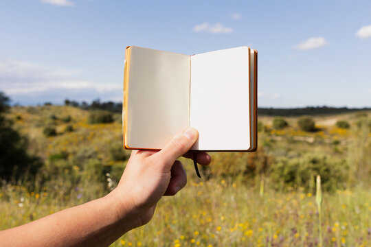 Open notebook held outdoors in a scenic open field