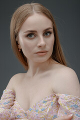 Young woman poses confidently with soft expressions in a delicate floral outfit against a neutral background