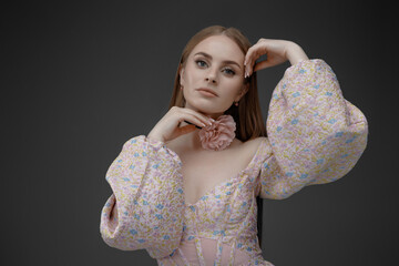 Model poses elegantly while showcasing a floral accessory in a studio setting during a fashion shoot