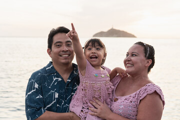 Happy hispanic family pointing and smiling at beach