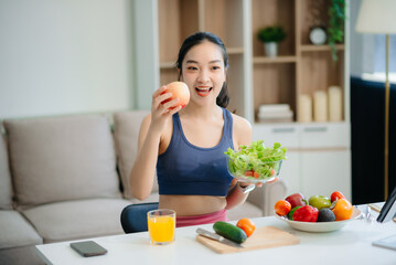 wellness as a cheerful woman enjoys a salad and fruits while engaging with technology at home