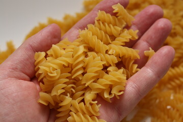A handful of dry pasta in hand on a blurred background. Selective focus.