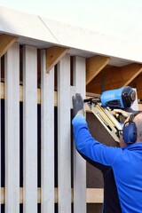 Man using pneumatic stapler, nail gun for wooden board, driving metal nails and staples.