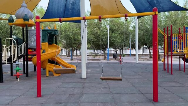 Vibrant 4K shot of a colorful playground with swings and a spiral slide. Ideal for childhood themes, urban parks, or public recreation content.
