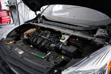 Car engine revealed under open hood in a professional work setting
