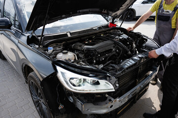 Mechanics Examining Vehicle Engine in Outdoor Workshop Setting