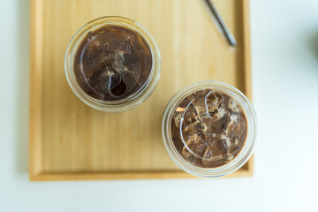 Refreshing americano coffee two takeaway glass with lid on a wooden tray