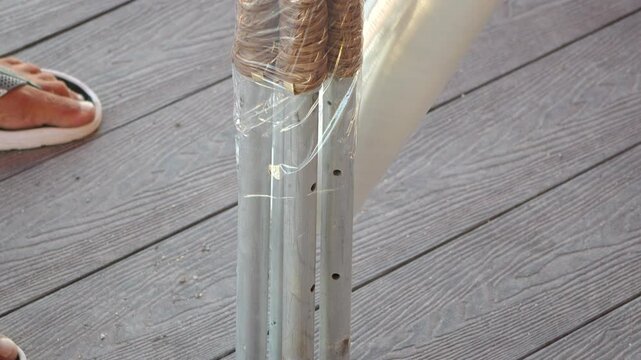 Deck Post Repair Wood Rot Wrap - A person is using a white plastic wrap to repair a wood post on a deck. The wrap is being applied around the post, where it has been damaged by rot.