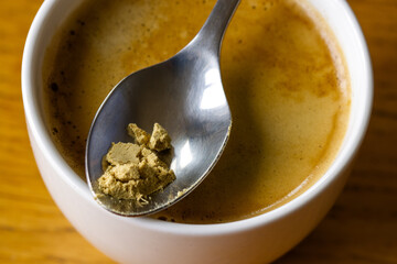 Cup of coffee on a wooden table, ground ginger on a spoon, coffee with the addition of ginger stimulating digestion.