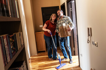 A married couple is cleaning their new apartment together. They organize belongings, wipe surfaces, and prepare the space to feel like home. 