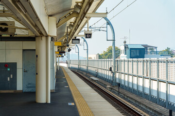 Modern railway platform in urban station with yellow tactile paving and overhead signal