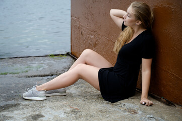 Woman in a black dress enjoys herself at the seashore.