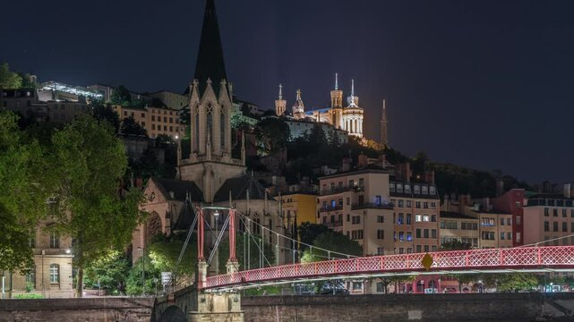 Timelapse hyperlapse of Saint George Church, Quais de Saone and Fourviere Basilica from a footbridge in Vieux Lyon, France, showcasing historic architecture at night, reflections and scenic river view