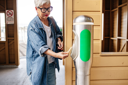Senior Asian woman scanning her concession card on tap on ticket machine