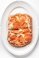 Close-up of a freshly baked pepperoni pizza slice with melted mozzarella cheese, sprinkled with herbs, served on a white plate. The crispy crust and rich tomato sauce enhance its appetizing appearance