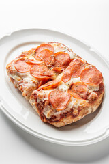 Close-up of a freshly baked pepperoni pizza slice with melted mozzarella cheese, sprinkled with herbs, served on a white plate. The crispy crust and rich tomato sauce enhance its appetizing appearance