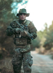Fototapeta premium Soldier walking in the forest holding a rifle during airsoft game