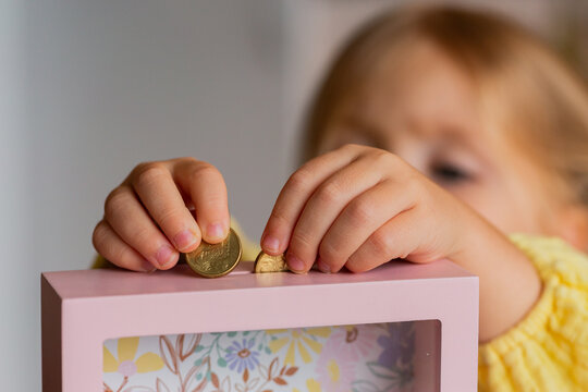 Aussie child putting Australian gold coins into moneybox at home