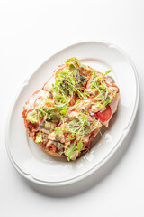 A golden, crispy Roman-style pinsa with a light, airy crust, topped with fresh greens, sliced tomatoes, melted cheese, and creamy dressing, served on a white plate for a delicious meal.