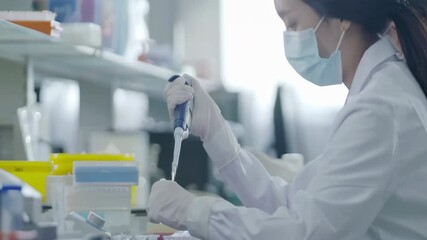 Researcher in medical protective gloves transferring Solution Samples into Test Tubes flasks with Suction Pipette for cell culture assay in biological cabinet on in cleanroom environmental facility - Powered by Adobe